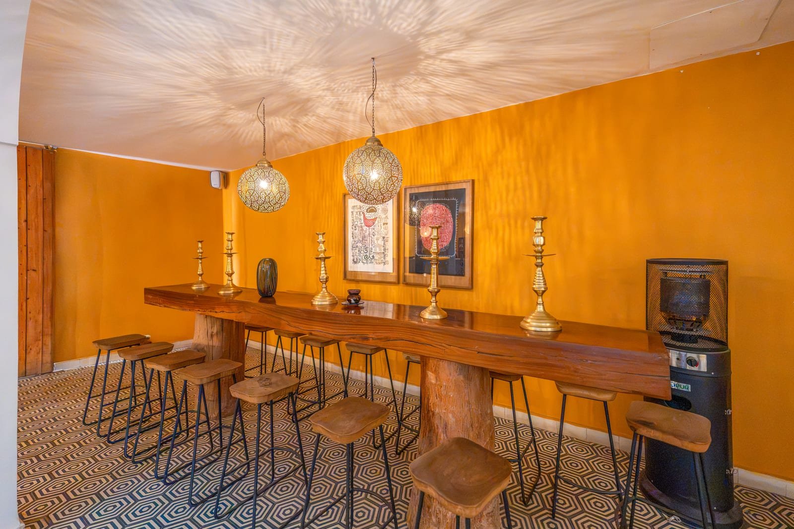 Le long comptoir de bois du bar, tabourets et suspensions de laiton ajouré