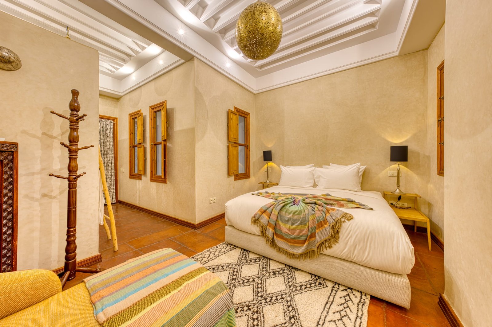 Une chambre aux murs de tadelakt clair, lustre de laiton ciselé et tapis berbère
