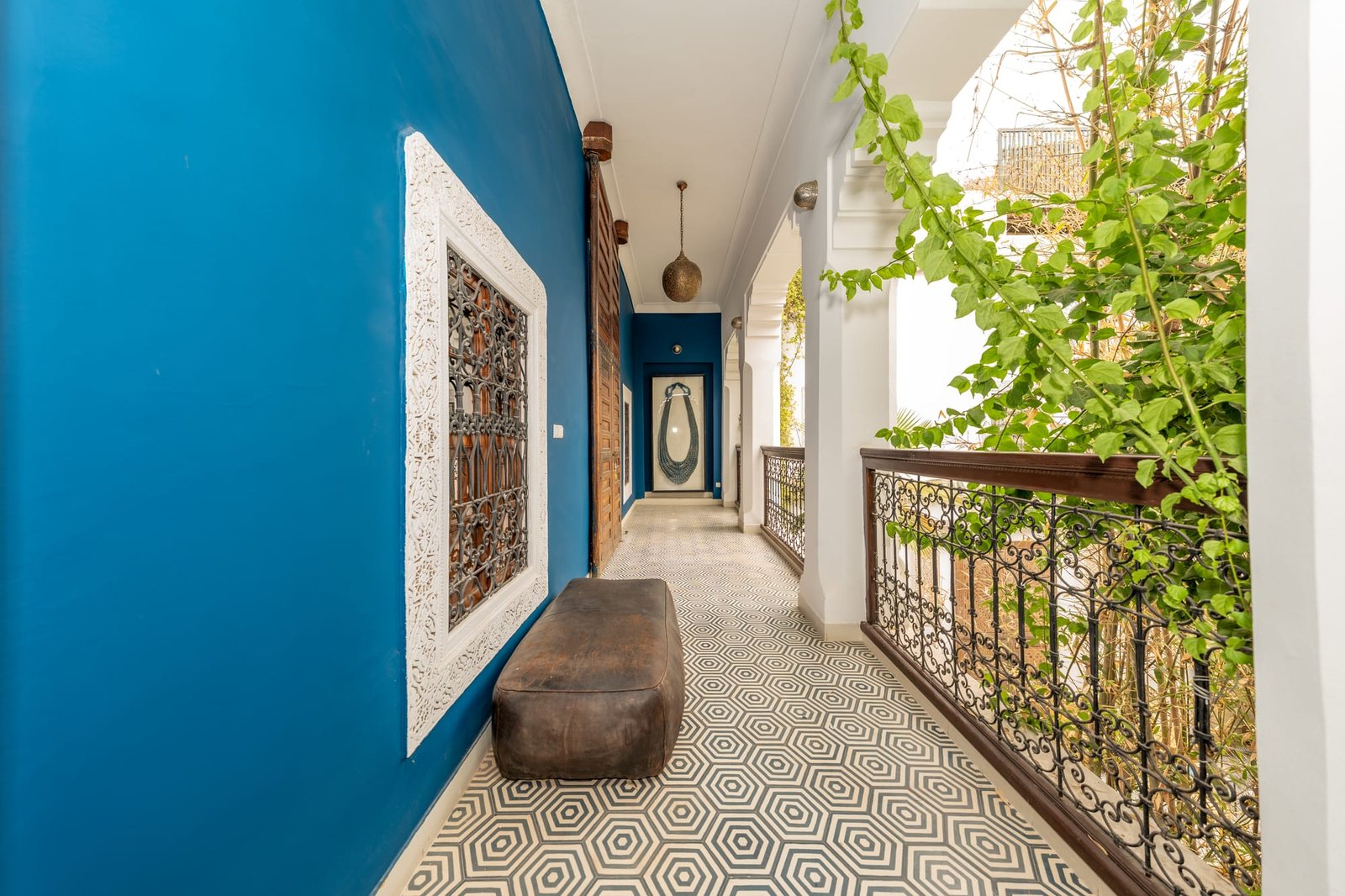La galerie de l’étage : mur bleu vif, rambarde en fer forgé et sol en carreaux de ciment