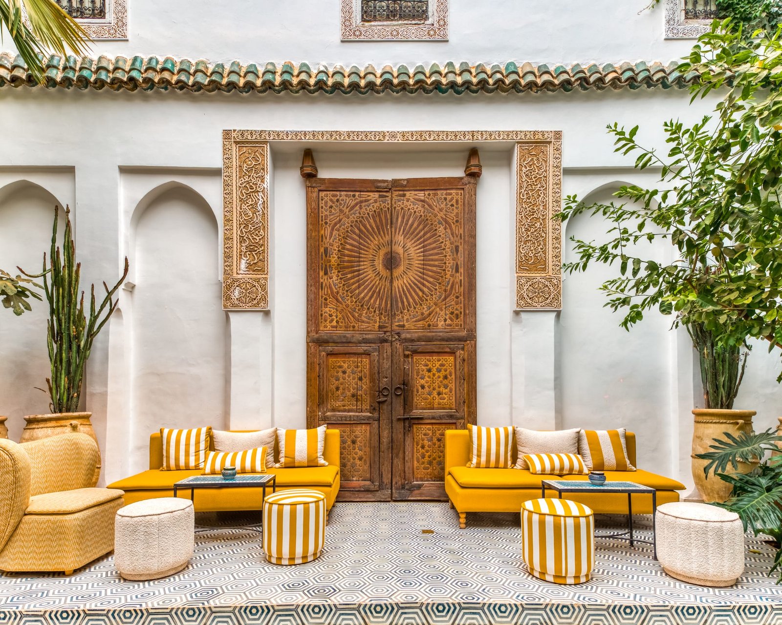 Le patio et sa grande porte de cèdre sculpté, banquettes safran et pots de terre cuite