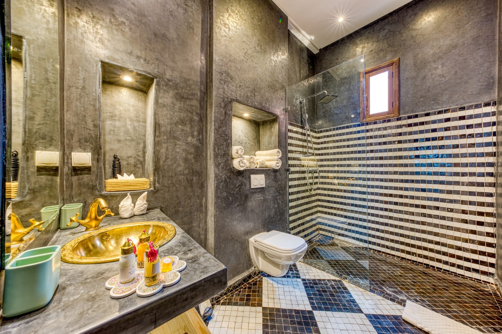 Une salle de bain en tadelakt, vasque de cuivre doré et douche en mosaïque