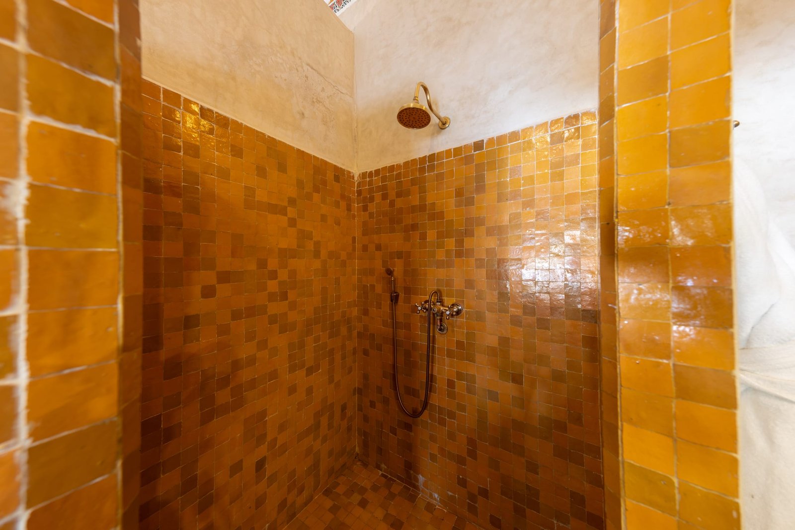 La douche du hammam, entièrement revêtue de zellige ocre
